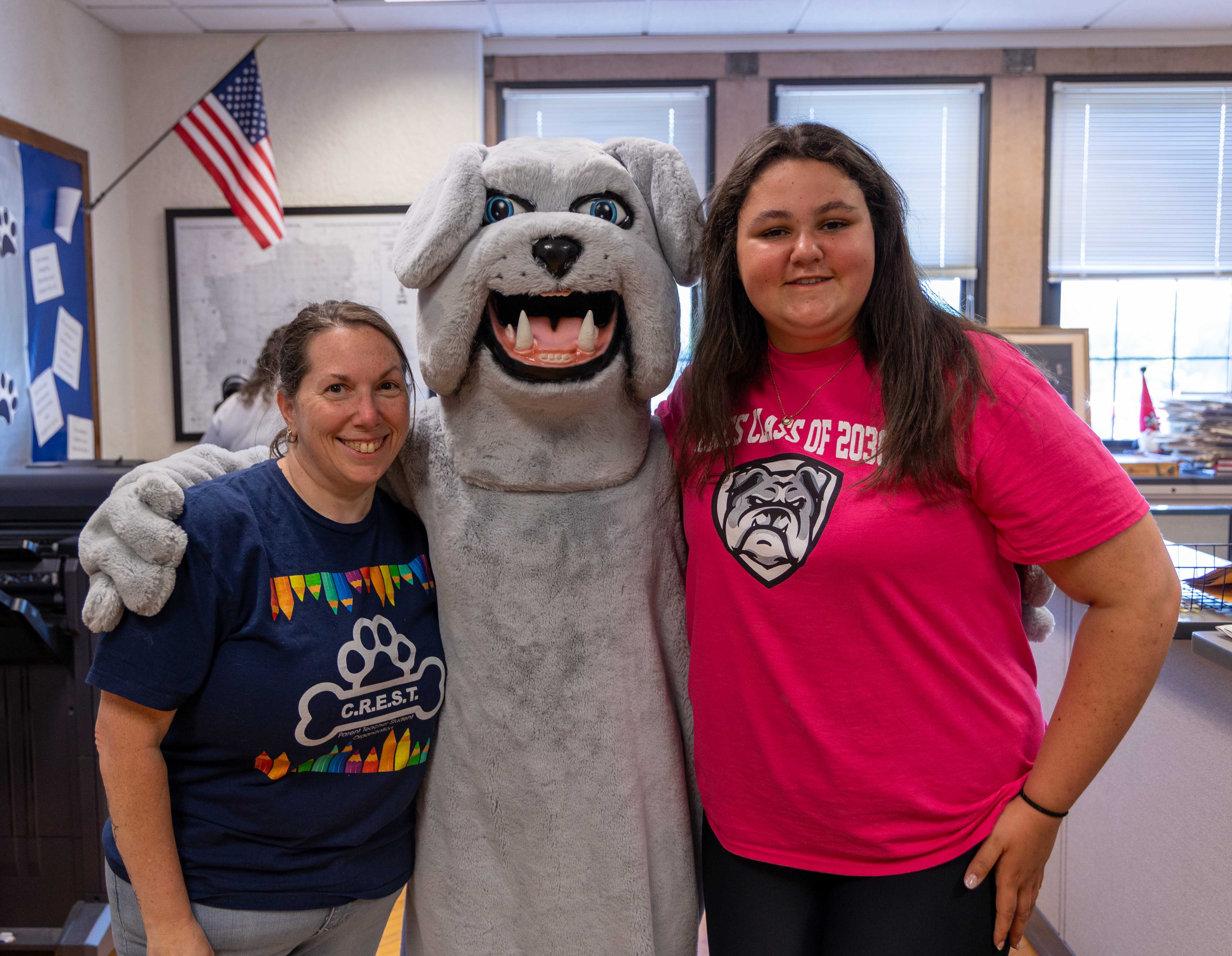 A CREST volunteer poses with a bulldog mascot and student